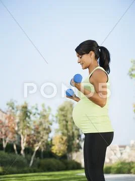 Pregnant Hispanic woman lifting weights outdoors Stock-Fotos