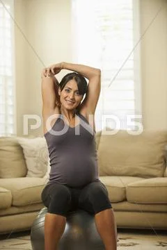 Pregnant Hispanic woman stretching on exercise ball Stock-Fotos