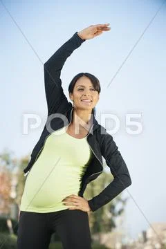 Pregnant Hispanic woman stretching outdoors Stock-Fotos