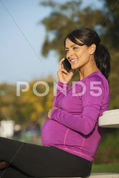 Pregnant Hispanic woman talking on cell phone Stock Photos