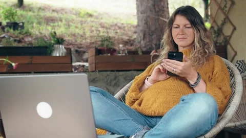 A pregnant middle-aged woman is using a smartphone while sitting on the terrace Stock Footage 292641553