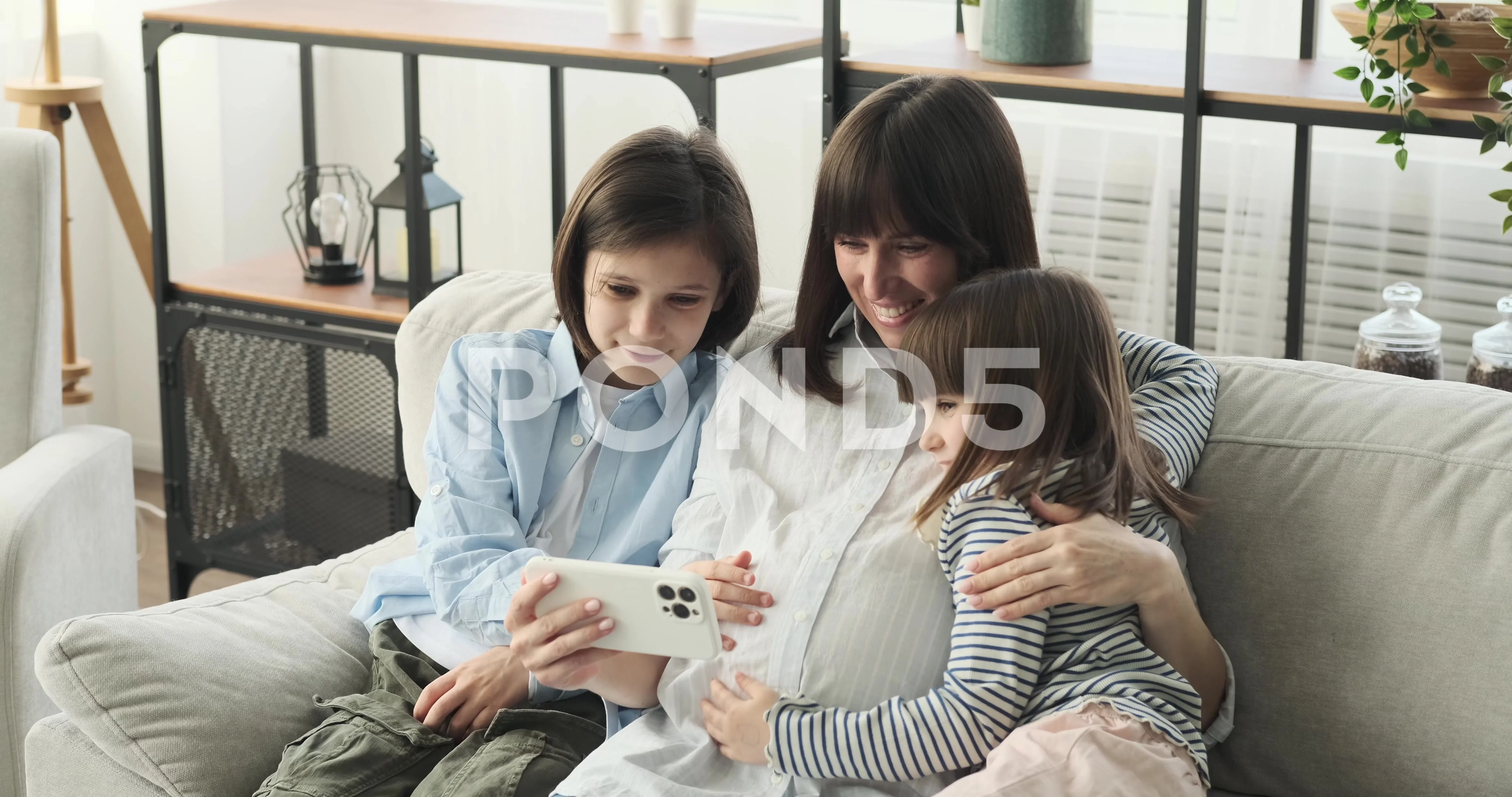 Family, video game and online gaming on home sofa with a pregnant mother  and daughter on a living room couch together while happy and having fun.  Woman and girl kid together for