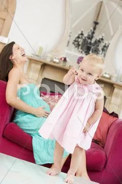Pregnant mother holding belly in pain with daughter pointing in foreground Stock-Fotos