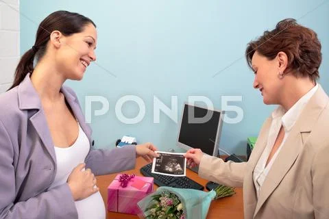 Pregnant office worker showing ultrasound to colleague Stock Photos