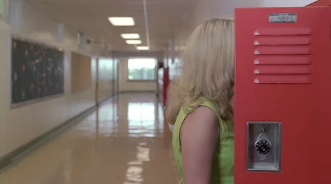 Pregnant teen getting textbooks from locker, walking down long hall as boys pass Stock Footage