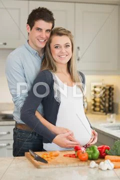 Pregnant woman and huband stand behind kitchen counter Stock Photos