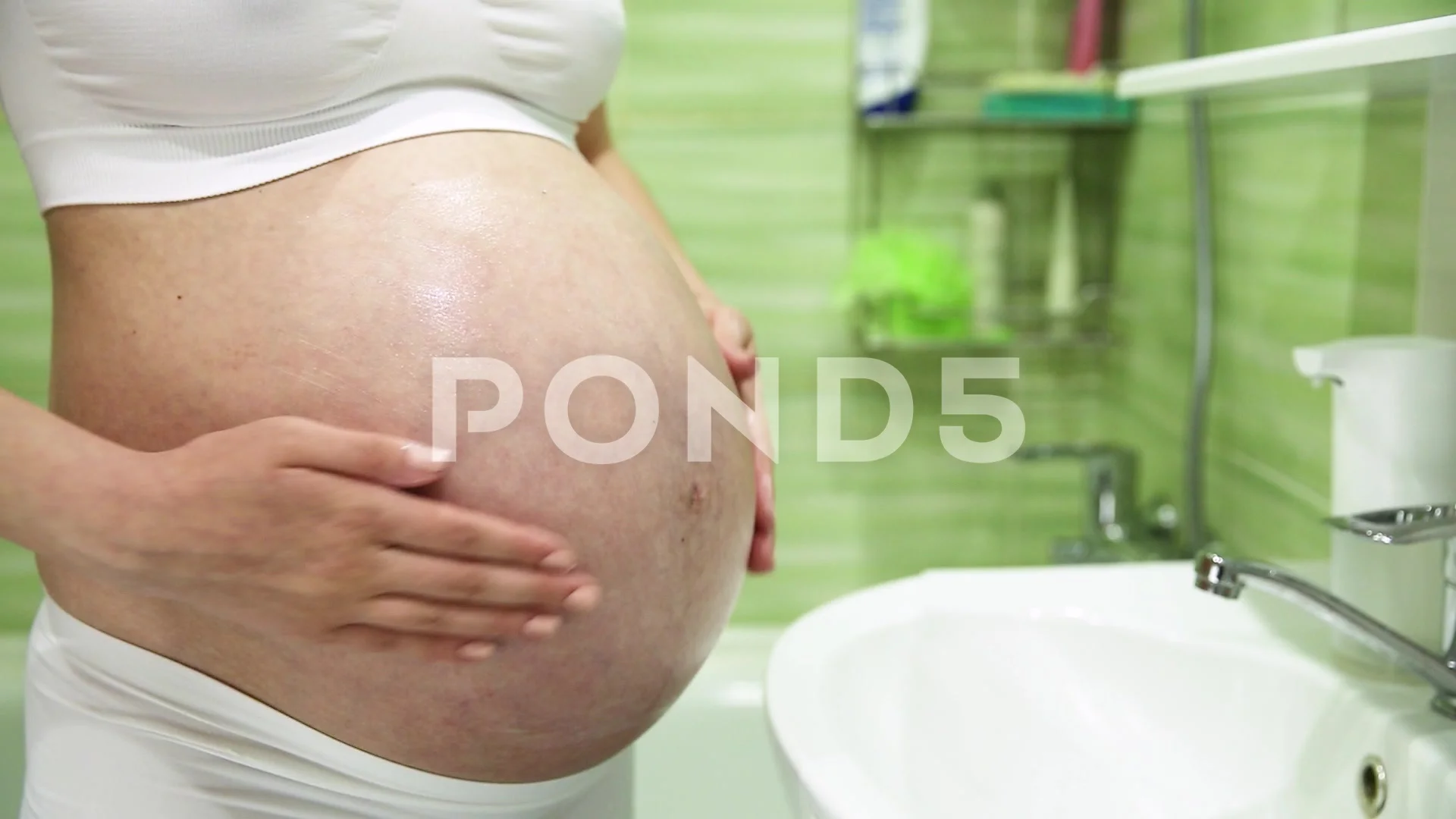 Pregnant woman is applying cream for stretch marks on her belly