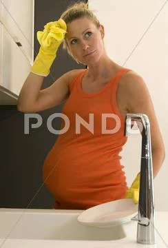 Pregnant woman cleaning kitchen Stock Photos