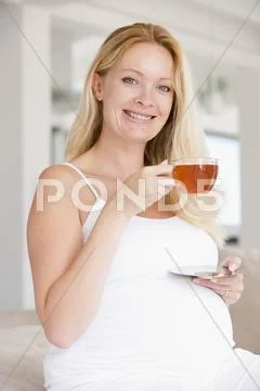 Pregnant woman with cup of tea smiling Stock Photos