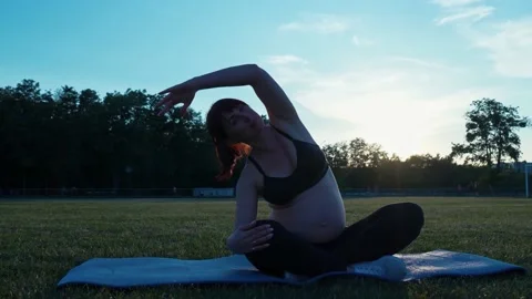 Pregnant woman doing stretching and yoga at sunset. Beautiful pregnant woman Stock Footage 197681553