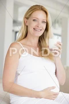 Pregnant woman with glass of milk smiling Stock Photos