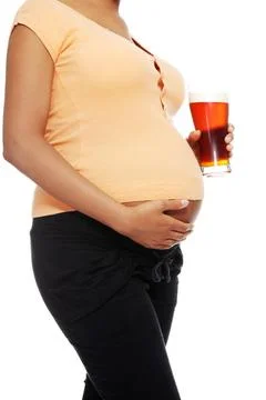 Pregnant woman holding a glass of alcohol next to her tummy Pregnant woman... Stock Photos