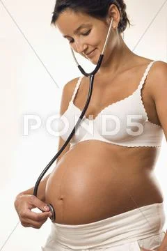 Pregnant woman holding stethoscope on belly, close-up Stock Photos