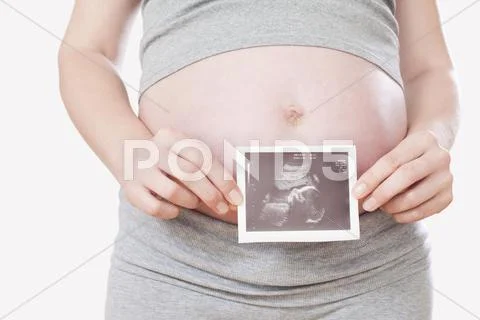 Pregnant woman, holding ultrasonic picture, mid-section Stock Photos