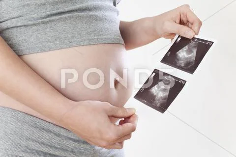 Pregnant woman holding ultrasonic pictures, mid-section Stock Photos