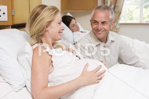 Pregnant woman with husband in hospital smiling Stock-Fotos
