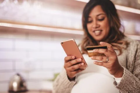 Pregnant woman shopping online with credit card and mobile phone Stock Photos