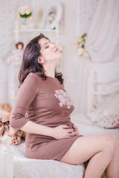 Pregnant woman sitting on a bed Stock Photos