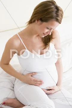 Pregnant woman sitting in bed smiling Stock Photos