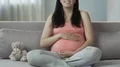Pregnant woman sitting on couch, rubbing stomach and smiling, happy pregnancy HD Footage