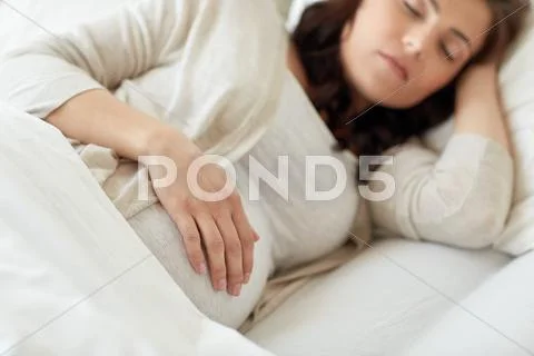 Pregnant woman sleeping in bed at home Stock Photos