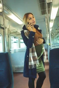Pregnant woman talking on mobile while travelling in train Stock Photos