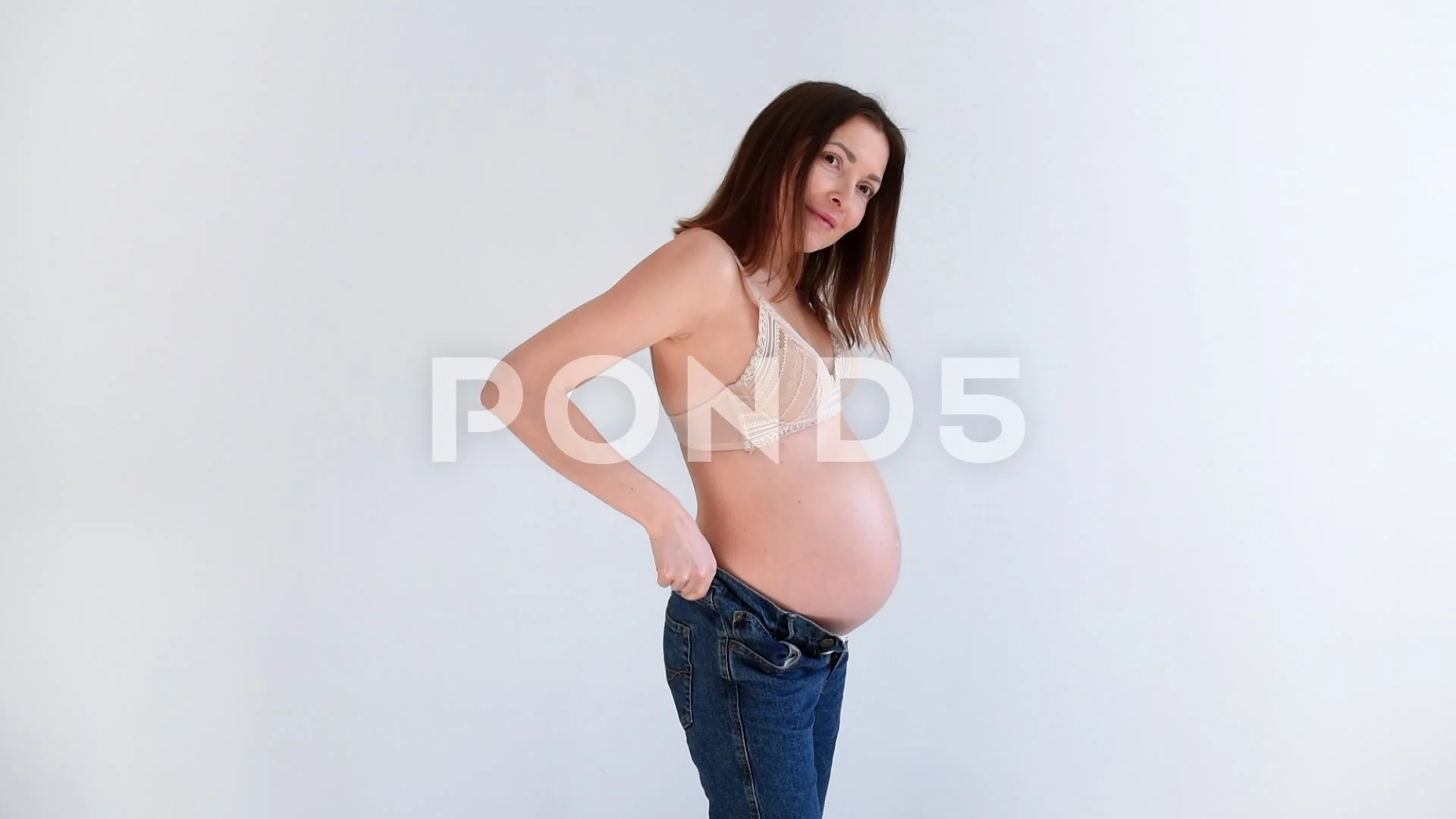 Pregnant woman in underwear puts on jean, Stock Video