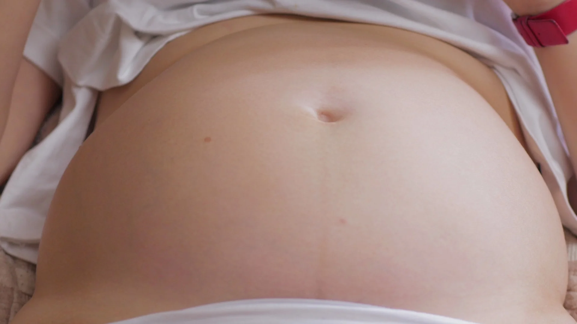 Pregnant womans belly with baby moving and kicking inside