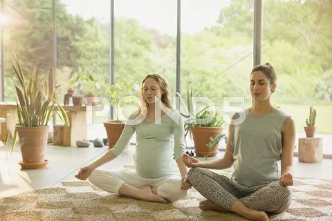 Pregnant women meditating in lotus position Stock Photos