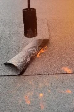 Preheating the edges of the roofing material. Stock Photos