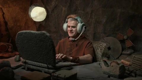 Prehistoric man wearing a headset and working in the office Stock Footage 333046513