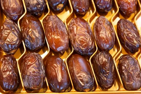 Premium dried dates with a glossy texture arranged in a golden tray. Perfect for Stock Photos