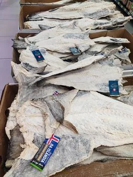 Premium dried salted cod fish piled in crates. This traditional seafood stapl Stock Photos