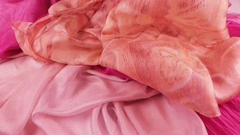 Premium peach silk fabric gently falls onto luxurious orange and pink scarfs. Stock-Footage 337405913