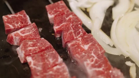 Premium Raw Wagyu Beef Cubes Grilling with Onions on Hot Plate Stock Footage 337440990