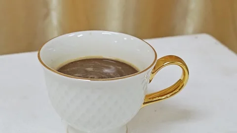Premium white ceramic coffee cup with golden handle on elegant background. Видео 344035393