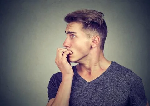 Preoccupied anxious man biting his fingernails looking to the side Stock Photos