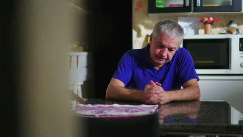 Preoccupied senior man at kitchen table ruminating problems, candid domesti.. Stock Photos
