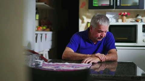 Preoccupied senior man at kitchen table ruminating problems, candid domesti.. Stock Photos