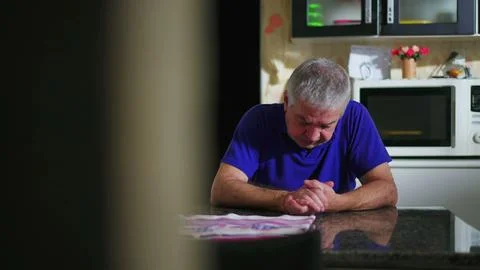Preoccupied senior man at kitchen table ruminating problems, candid domesti.. Stock Photos