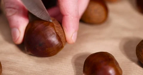 Preparation by cutting the shells of edible chestnut nuts for baking, closeup Stock Footage 312165520