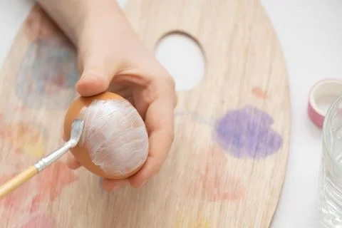 Preparation for Easter. The child is holding a large egg in his hands. Pastel Stock Photos