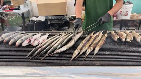 Preparation of Fish on Grill. Hands of chef flipping long whole fish on open Stock-Footage 316917946