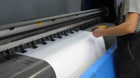 Preparation for the large-format inkjet printing press. The male hands of the Stock Footage
