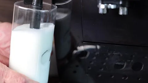 Preparation of latte - the coffee maker froths milk in a glass of milk. Stock Footage 247906390