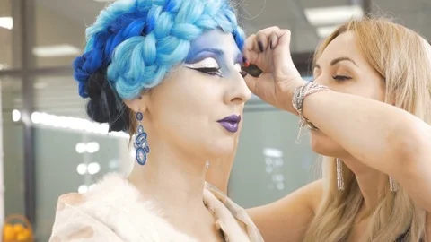 Preparation of the model for a photo shoot. The make-up artist adjusts her hair. Video stock 85452981