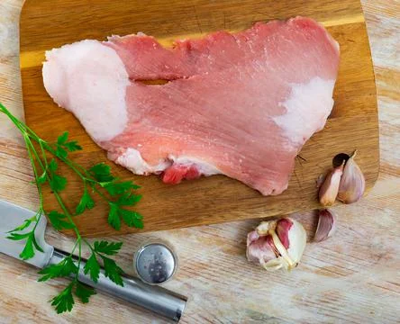 Preparation of raw pork secreto fillet on kitchen board Stock Photos