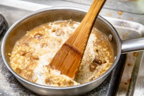 Preparation of risotto with mushrooms in the restaurant kitchen. Stock Photos