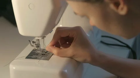 Preparation for sewing. Seamstress inserts thread in needle of sewing machine. Stock Footage 137782785