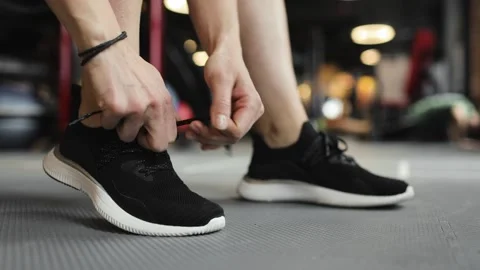 Preparation for training. Close-up of legs of young woman tying laces on Stock Footage 158758457